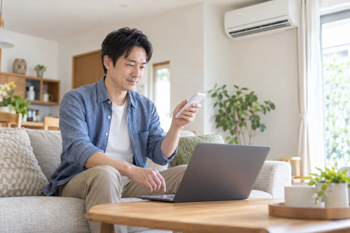 パソコンで手順を確認しながらエアコンを操作する男性